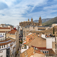 Aerial view of Jaén's old town rooftops and cathedral with mountains in the background.
