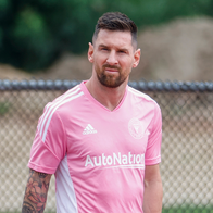 Lionel Messi in an Inter Miami training kit standing on a football pitch.