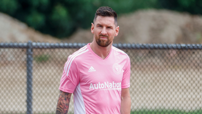 Lionel Messi in an Inter Miami training kit standing on a football pitch.