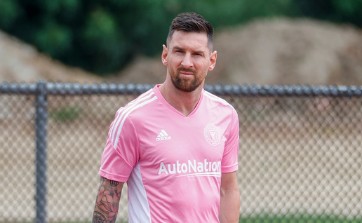 Lionel Messi in an Inter Miami training kit standing on a football pitch.