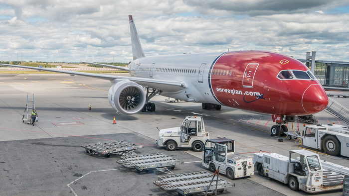 Norwegian aircraft parked at a terminal outside the Oslo Gardermoen airport.