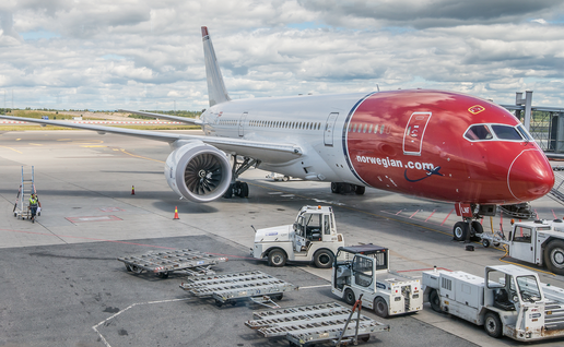 Norwegian aircraft parked at a terminal outside the Oslo Gardermoen airport.