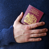 Close-up of a person holding a British passport against their chest.