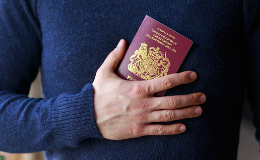 Close-up of a person holding a British passport against their chest.