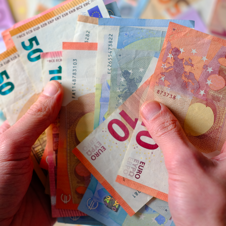 A hand holding different amounts of euro bank notes