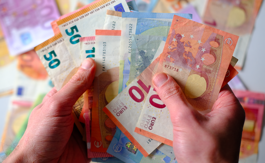A hand holding different amounts of euro bank notes