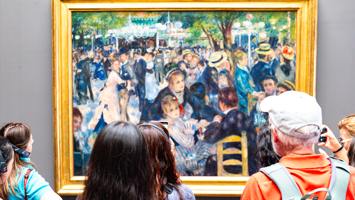 Tourists looking at a framed painting of Renoir