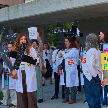 Doctors outside a hospital protesting with signs and banners asking for better pay and working hours for doctors