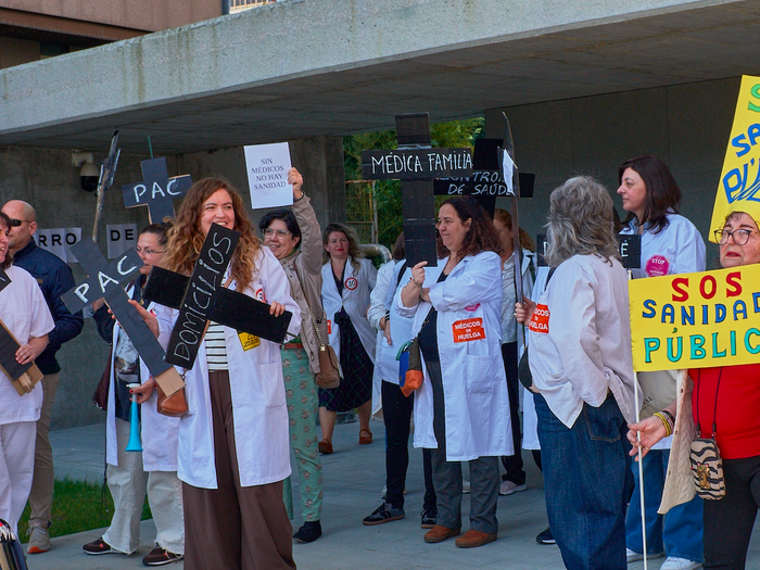 Doctors outside a hospital protesting with signs and banners asking for better pay and working hours for doctors