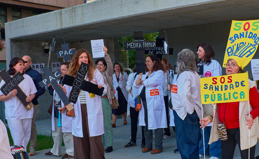Doctors outside a hospital protesting with signs and banners asking for better pay and working hours for doctors