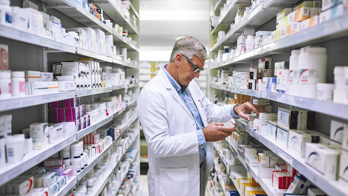 A pharmacist looking for medication amongst the shelves