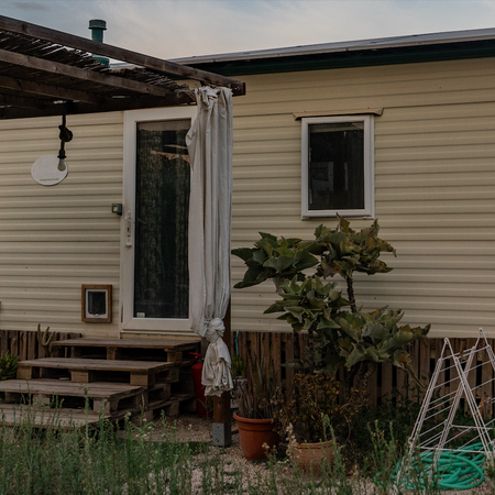 A mobile home with pergola and plants at the entrance
