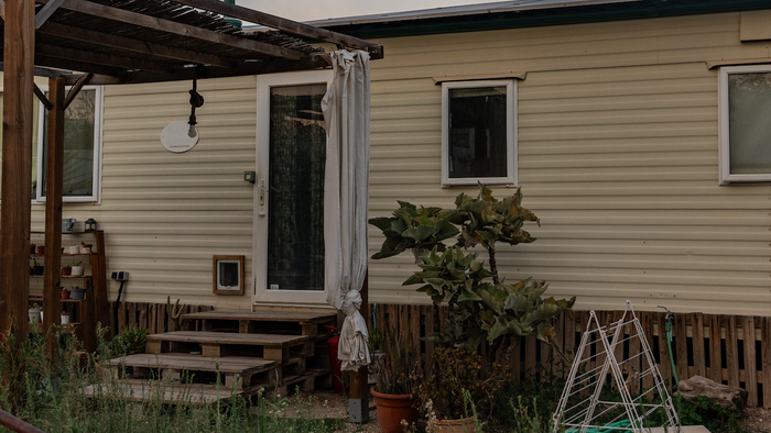 A mobile home with pergola and plants at the entrance