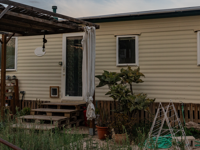A mobile home with pergola and plants at the entrance