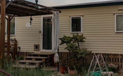 A mobile home with pergola and plants at the entrance