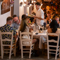 Diners eating outdoors at a restaurant next to a busy street