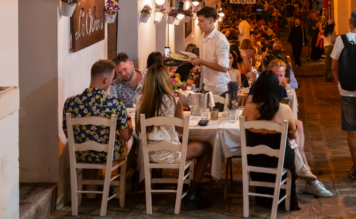 Diners eating outdoors at a restaurant next to a busy street