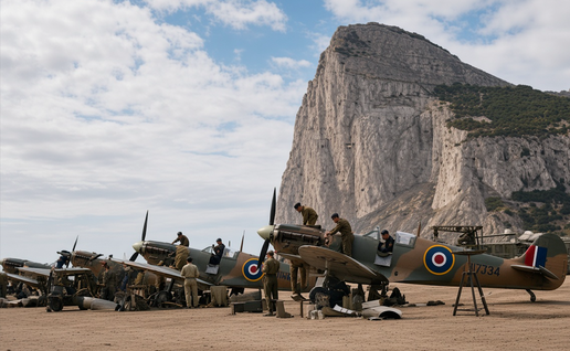 Colorized WWII photo of RAF Spitfires being serviced on the airfield at Gibraltar, with the Rock of Gibraltar in the background.