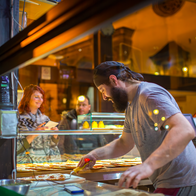 A man working at an Italian restaurant making pizza