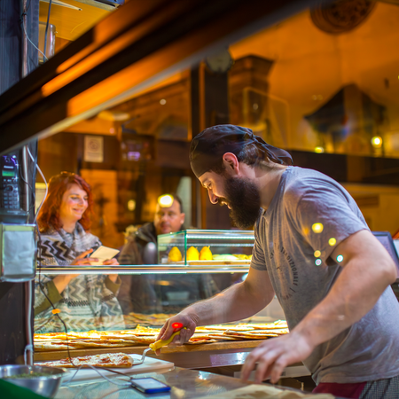 A man working at an Italian restaurant making pizza