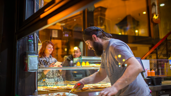 A man working at an Italian restaurant making pizza