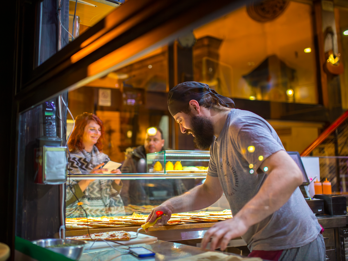 A man working at an Italian restaurant making pizza