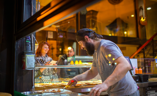 A man working at an Italian restaurant making pizza