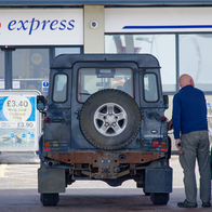 A man refuels a Land Rover Defender at a Tesco Express petrol station in the UK.