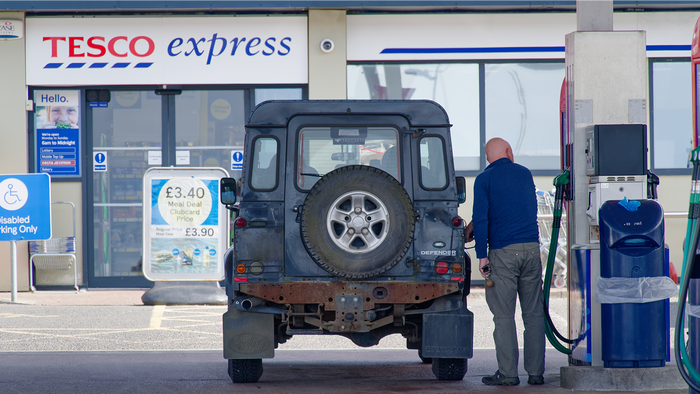 A man refuels a Land Rover Defender at a Tesco Express petrol station in the UK.