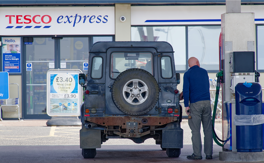 A man refuels a Land Rover Defender at a Tesco Express petrol station in the UK.