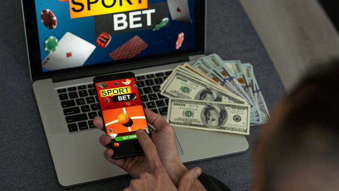 Man watching football play online broadcast on his laptop, cheering for his favourite team, making bets at bookmaker's website