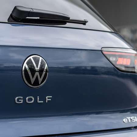Close-up of the rear badge and taillight of a dark blue Volkswagen Golf.