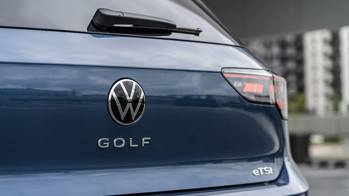 Close-up of the rear badge and taillight of a dark blue Volkswagen Golf.