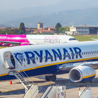 A Ryanair Boeing 737 parked at an airport gate with a Wizz Air Airbus taxiing behind it.