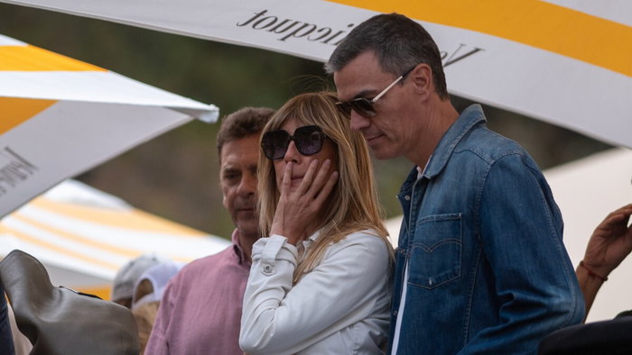 Begoña Gómez stands beside Pedro Sánchez at an outdoor public event in Spain.