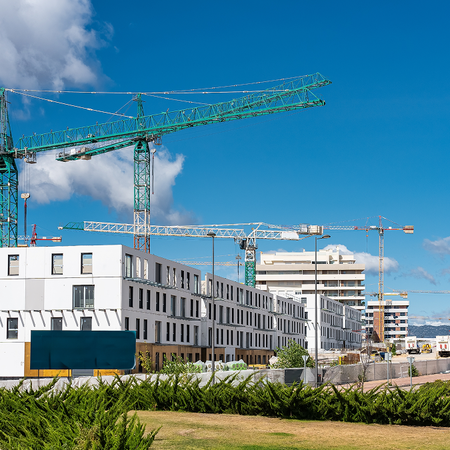 Construction cranes rise above newly built apartment blocks in a residential development in Spain.