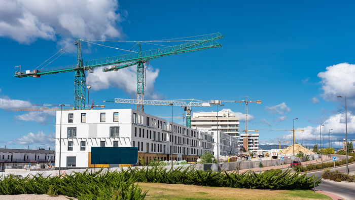 Construction cranes rise above newly built apartment blocks in a residential development in Spain.