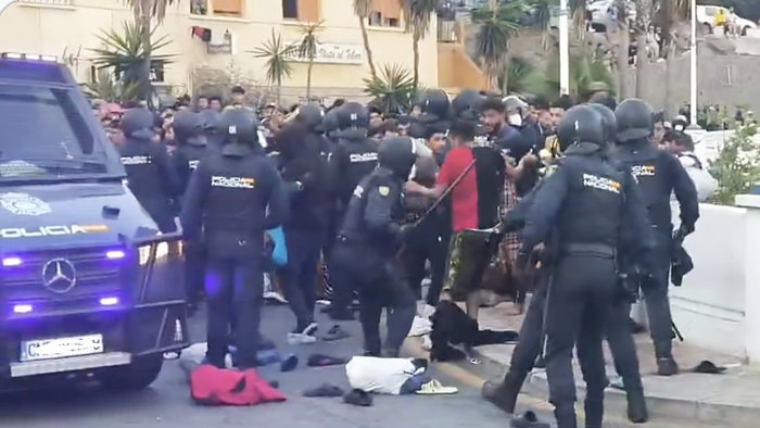 Spanish National Police officers intervene as a large crowd gathers during the Ceuta camp operation.