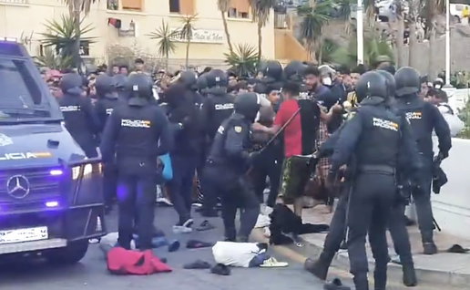 Spanish National Police officers intervene as a large crowd gathers during the Ceuta camp operation.