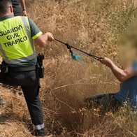 Guardia Civil officers detaining a blurred-face suspect in dry grass field after robbery.
