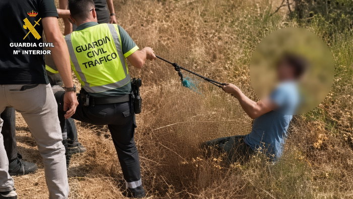 Guardia Civil officers detaining a blurred-face suspect in dry grass field after robbery.