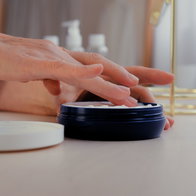 Woman's hand applying wrinkle cream from a pot