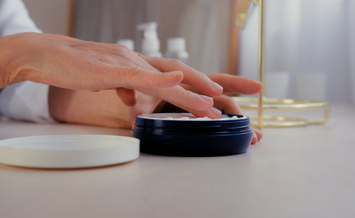 Woman's hand applying wrinkle cream from a pot