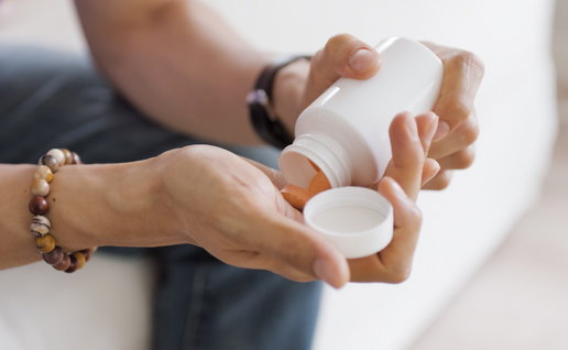a man sitting down and emptying some pills into his hands from a pot