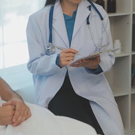 A female doctor sitting next to a male patient writing down notes
