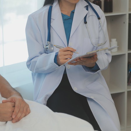 A female doctor sitting next to a male patient writing down notes