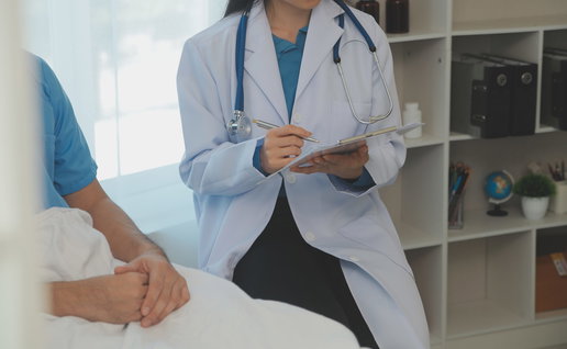 A female doctor sitting next to a male patient writing down notes