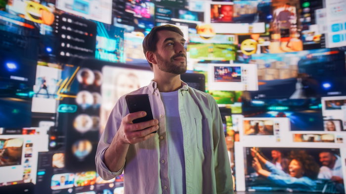 Portrait of Caucasian Man Using Smartphone in Metaverse With Animated Stream Of Interfaces With Social Media, e-Commerce Shopping, Internet Influencers And Games. Visualization Of Web Network.