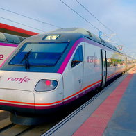 Two Renfe train parked at the train station with passengers waiting to board