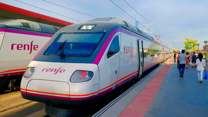 Two Renfe train parked at the train station with passengers waiting to board